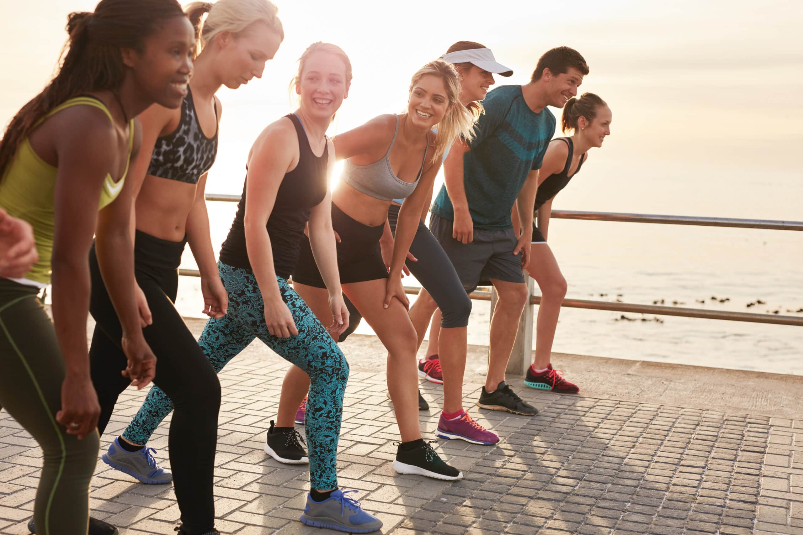 adults smiling, about to start a race at an outdoor boardwalk